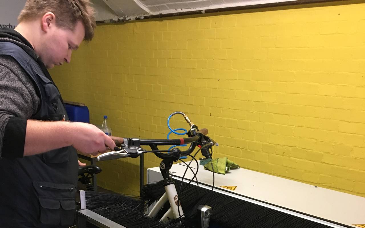 Mitarbeiter Stephan Gerke von der Radstation führt das dreckige Fahrrad durch die Farradwaschanlage.