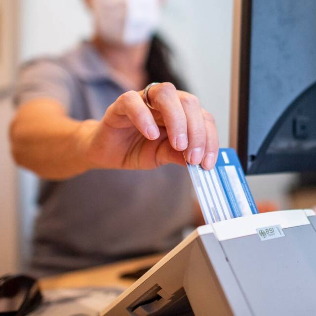 Eine Person schiebt eine Versichertenkarte einer Krankenkasse in eine Lesegerät. Elektronische Rezepte und digitale Patientenakten sollen nach jahrelangen Verzögerungen auf breiter Front zum Einsatz kommen. Darauf zielen Gesetzespläne von Gesundheitsminister Lauterbach (SPD), die das Bundeskabinett am Mittwoch in Meseberg auf den Weg gebracht hat.
