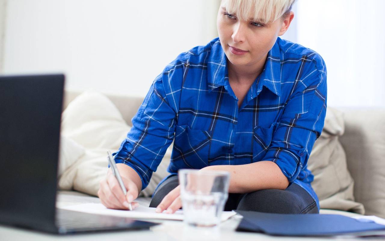 Frau macht sich neben einem Laptop Notizen