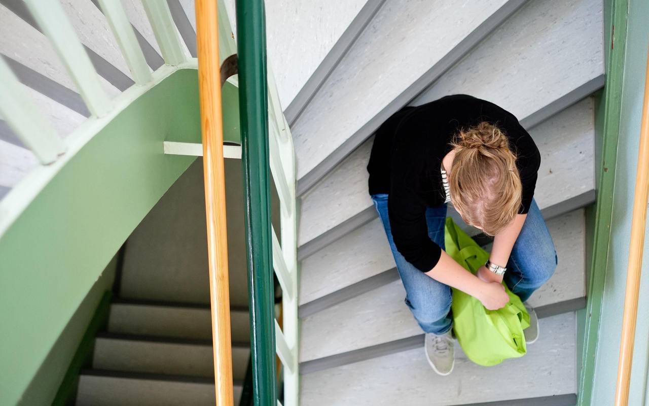 Eine Frau sitzt in einem Treppenhaus auf einer Treppenstufe