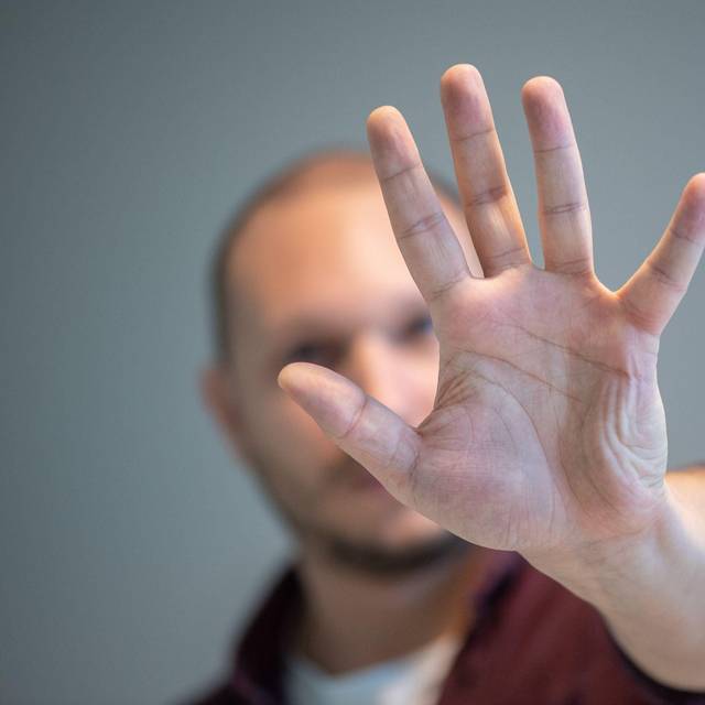 Ein Mann hebt schützend die Hand vor sein Gesicht