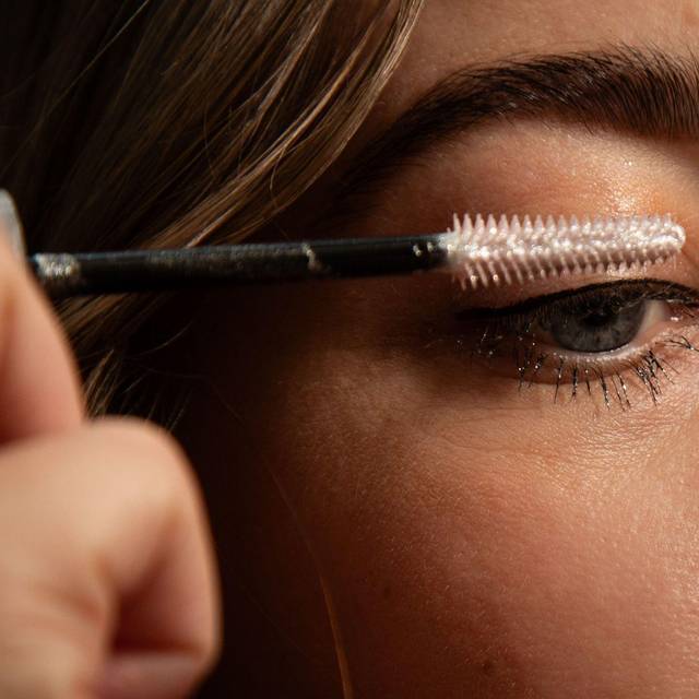 Frau tuscht sich die Wimpern mit Glitzer-Mascara