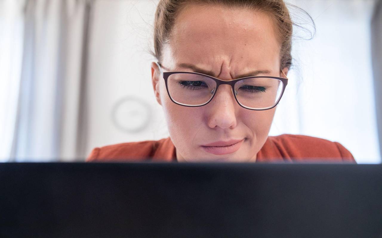 Eine junge Frau blickt skeptisch auf ihren Laptop