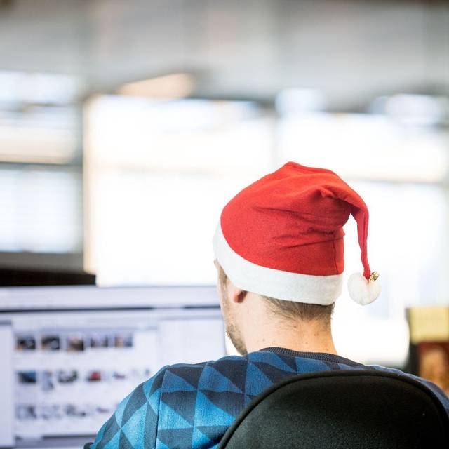 Ein Mann sitzt mit einer Weihnachtsmütze in Büro
