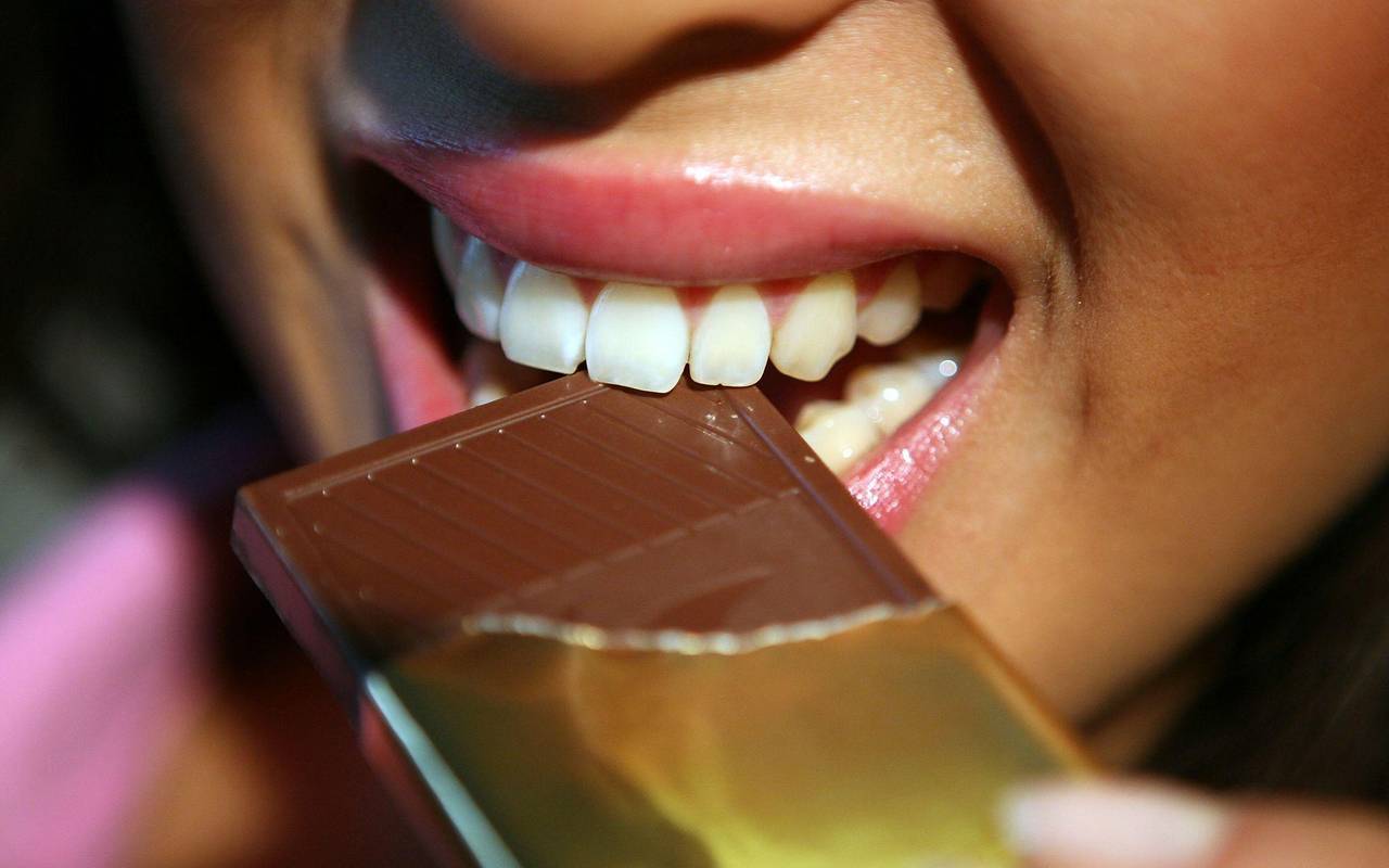 Frau beißt in eine Tafel Schokolade