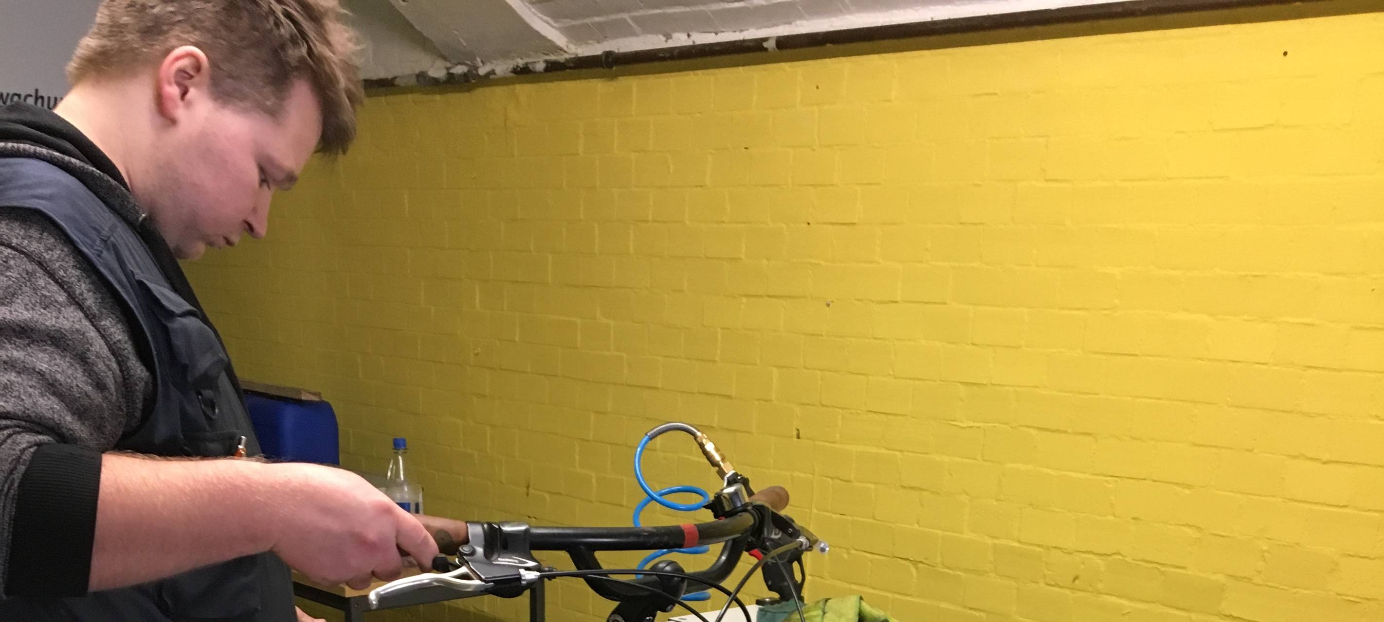 Mitarbeiter Stephan Gerke von der Radstation führt das dreckige Fahrrad durch die Farradwaschanlage.