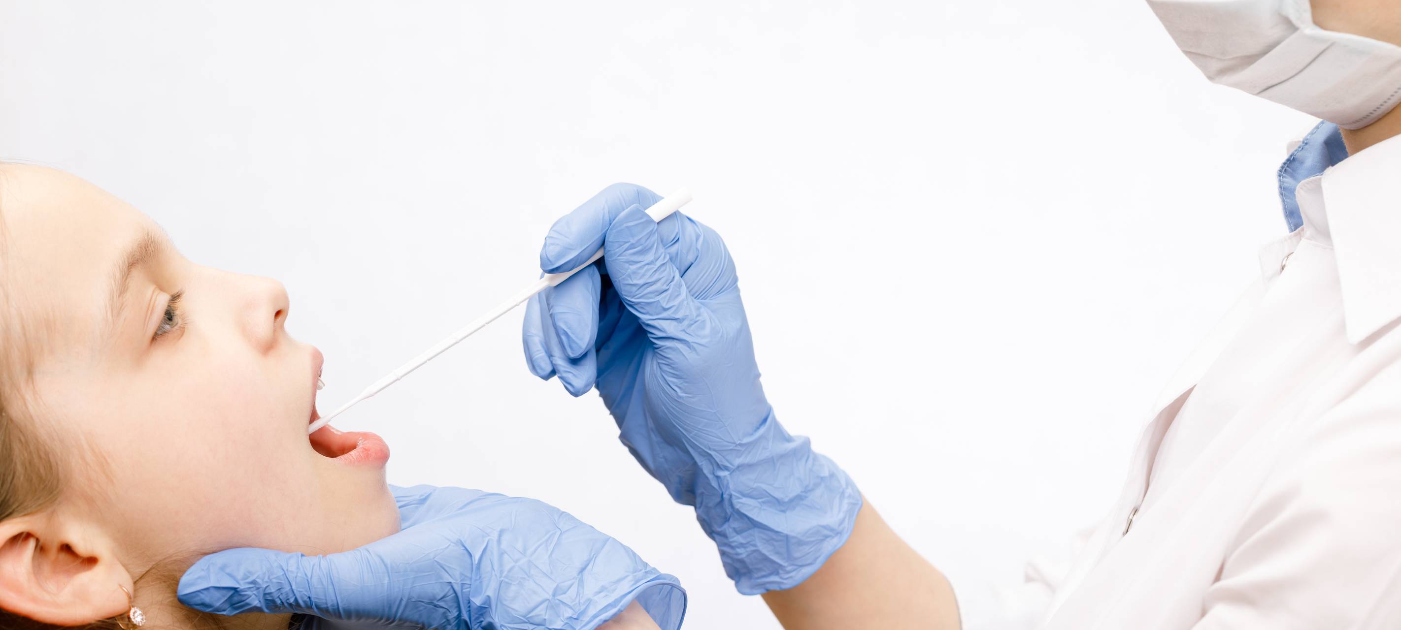 Arzt, der Speichelprobe aus dem Mund des Patienten entnimmt und dabei das diagnostische Verfahren für Speicheluntersuchungen durchführt.