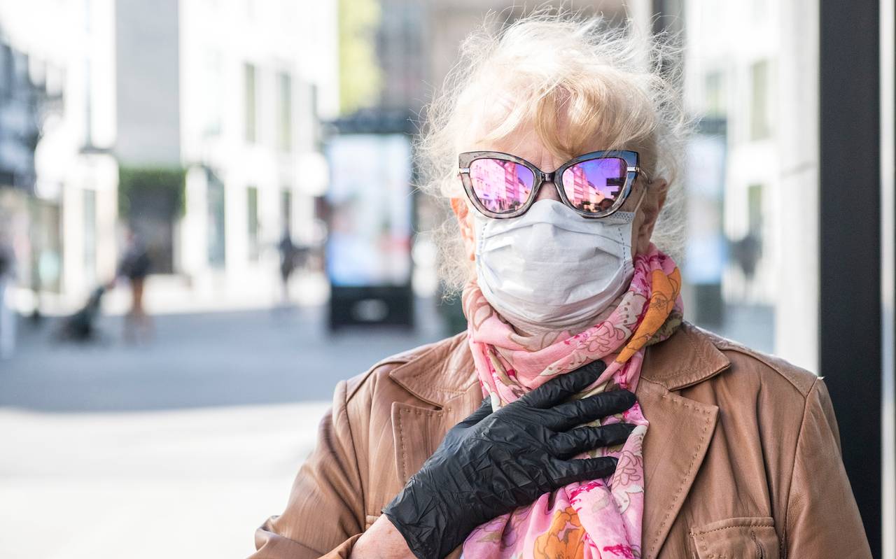 Eine Frau mit Mundschutz und verspiegelter Sonnenbrille auf der Flingerstrasse in Düsseldorf. Durch die Lockerung des Shutdowns dürfen einige Geschäfte wieder öffnen.