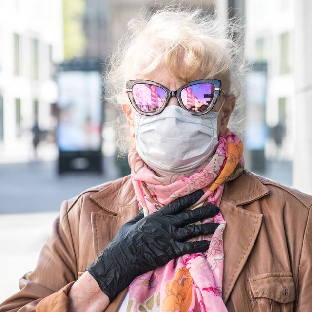 Eine Frau mit Mundschutz und verspiegelter Sonnenbrille auf der Flingerstrasse in Düsseldorf. Durch die Lockerung des Shutdowns dürfen einige Geschäfte wieder öffnen.