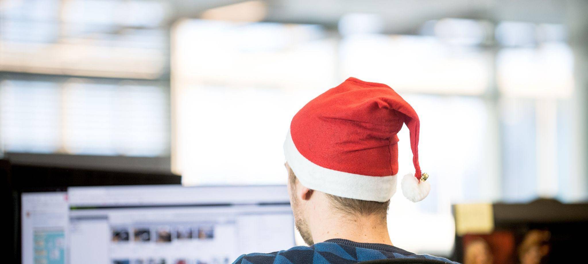Ein Mann sitzt mit einer Weihnachtsmütze in Büro