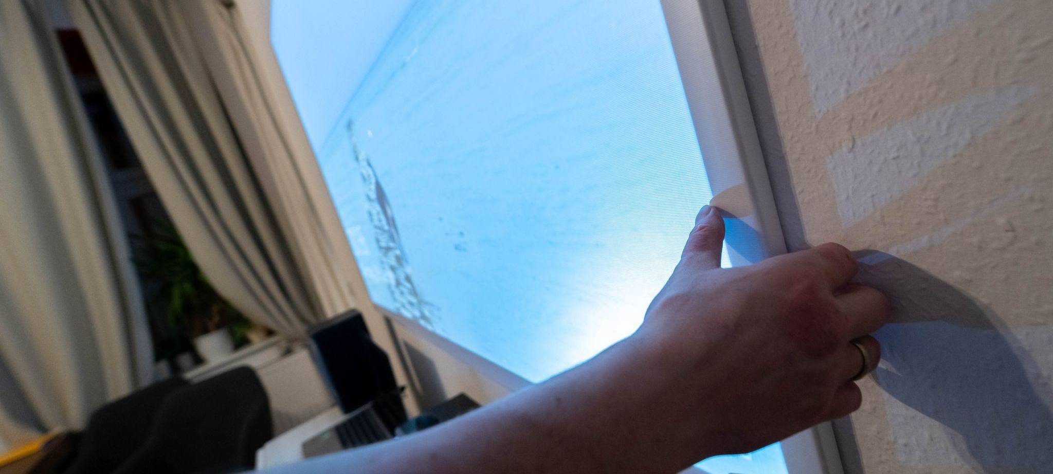 Ein Mann hängt eine Beamer-Leinwand auf