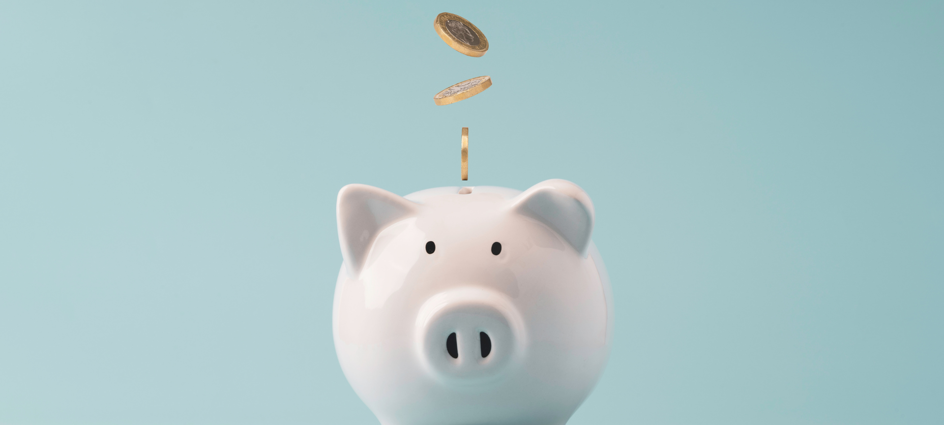 Minimalismus / weißes Sparschwein mit Kleingeld, hellblauer Hintergrund