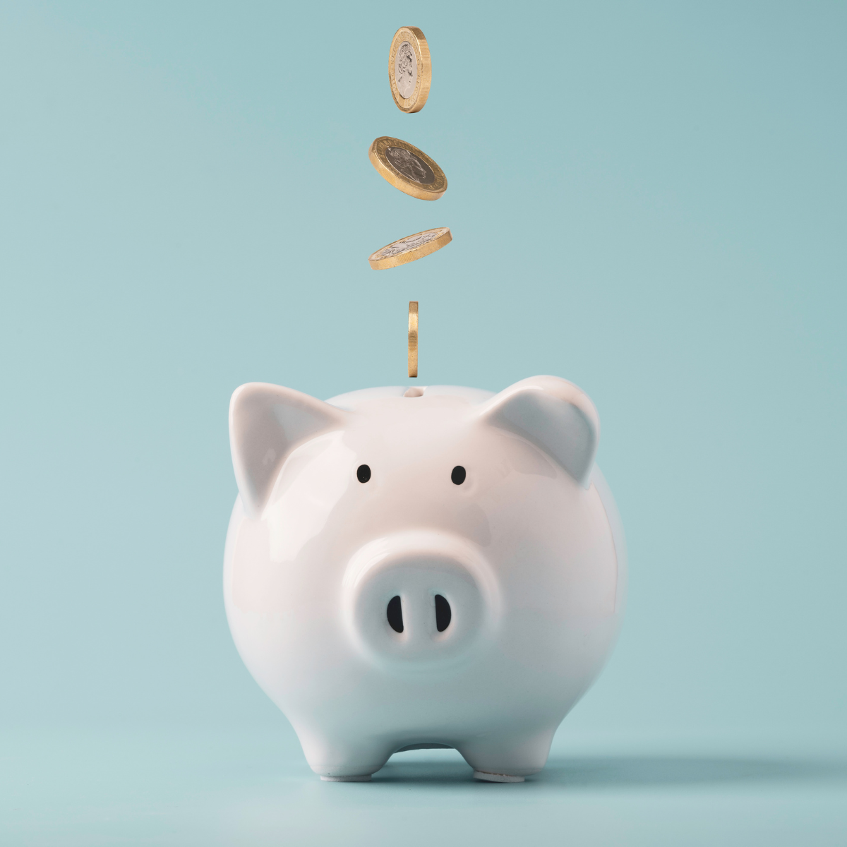 Minimalismus / weißes Sparschwein mit Kleingeld, hellblauer Hintergrund