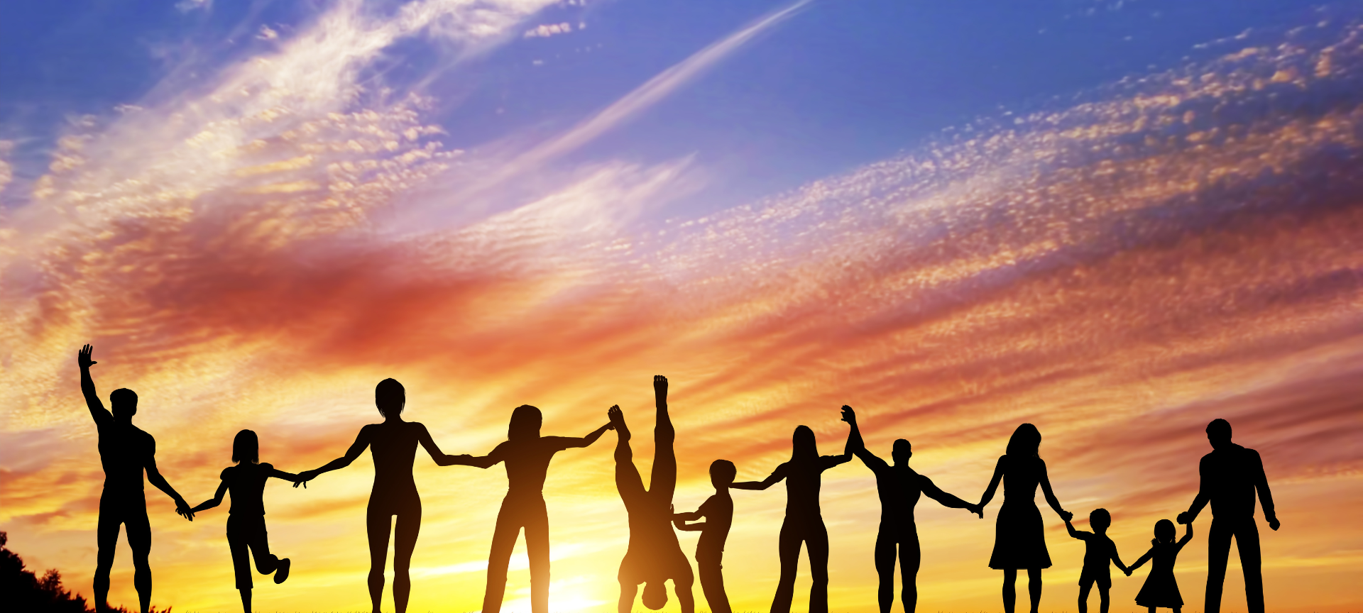 Neujahrsvorsätze / viele Menschen klein und groß stehen Hand in Hand unter freiem Himmel während die Sonne untergeht